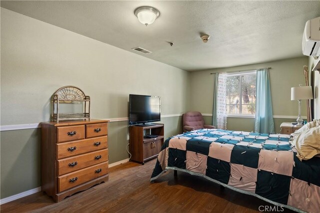 bedroom featuring a wall mounted AC and dark hardwood / wood-style flooring