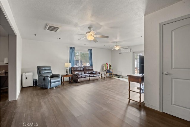 living room featuring a wall mounted AC, ceiling fan, hardwood / wood-style floors, and a textured ceiling