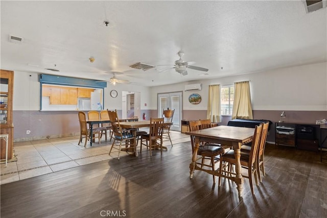 dining space featuring a wall mounted AC, ceiling fan, french doors, and wood-type flooring