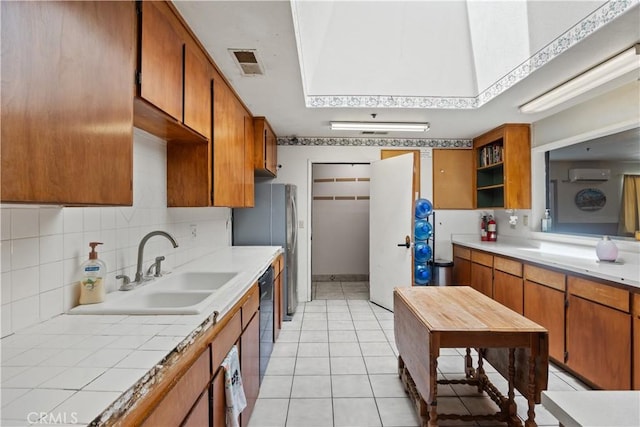 kitchen with sink, black dishwasher, a wall unit AC, decorative backsplash, and light tile patterned flooring