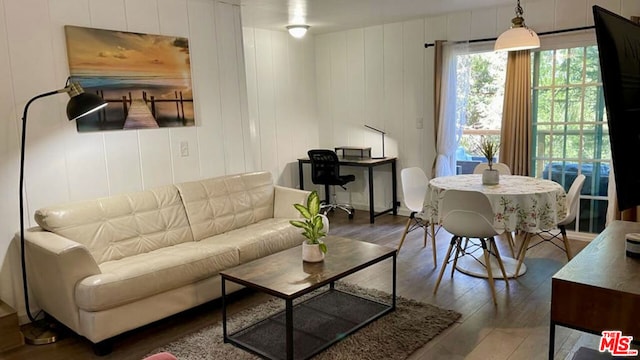 living room with hardwood / wood-style flooring and wooden walls