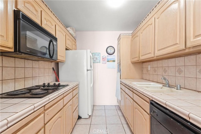 kitchen featuring light tile patterned flooring, light brown cabinets, tile counters, and black appliances