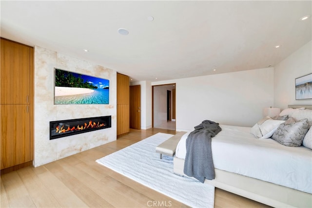 bedroom with light hardwood / wood-style flooring and a large fireplace