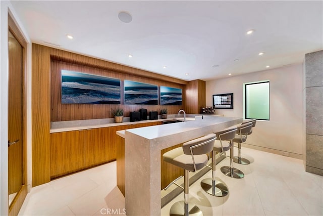 kitchen with sink, a kitchen bar, a kitchen island with sink, and light tile patterned flooring