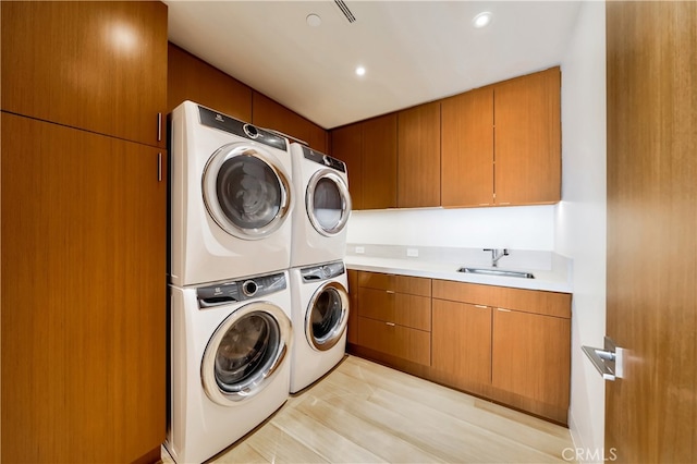 laundry area with sink, washing machine and clothes dryer, cabinets, light wood-type flooring, and stacked washer / drying machine