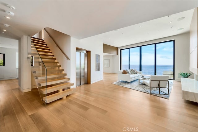 living room with light hardwood / wood-style flooring, elevator, and a water view