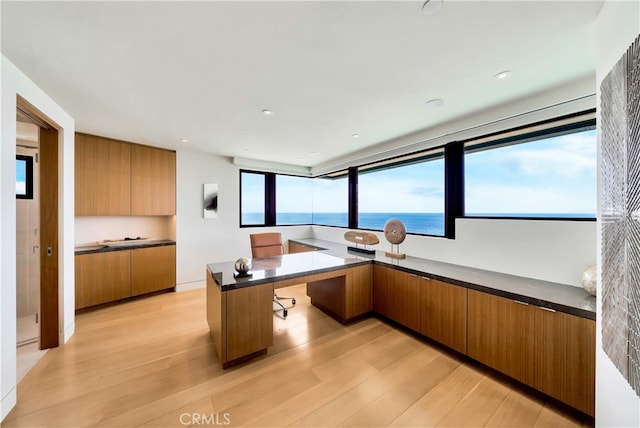 kitchen featuring a breakfast bar area, light hardwood / wood-style flooring, a water view, and kitchen peninsula