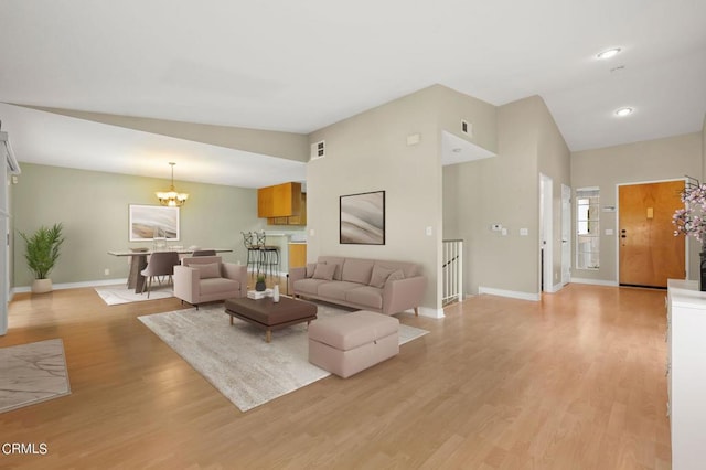 living room featuring light wood-type flooring, an inviting chandelier, and vaulted ceiling