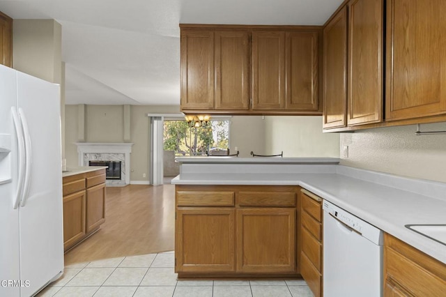 kitchen with kitchen peninsula, a high end fireplace, white appliances, and light wood-type flooring