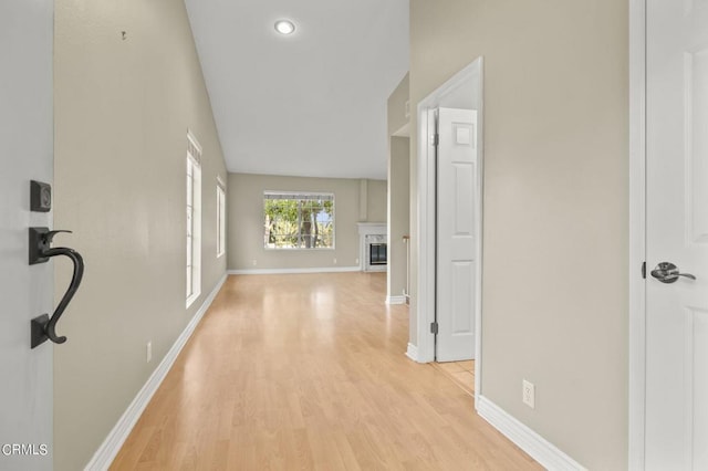 hallway featuring lofted ceiling and light wood-type flooring