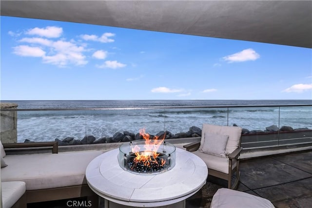 view of patio / terrace with a water view, an outdoor living space with a fire pit, and a balcony