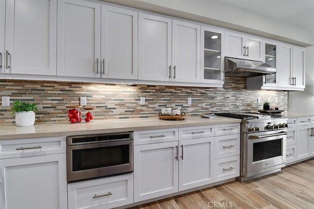 kitchen featuring light hardwood / wood-style flooring, decorative backsplash, stainless steel range, wall oven, and white cabinetry