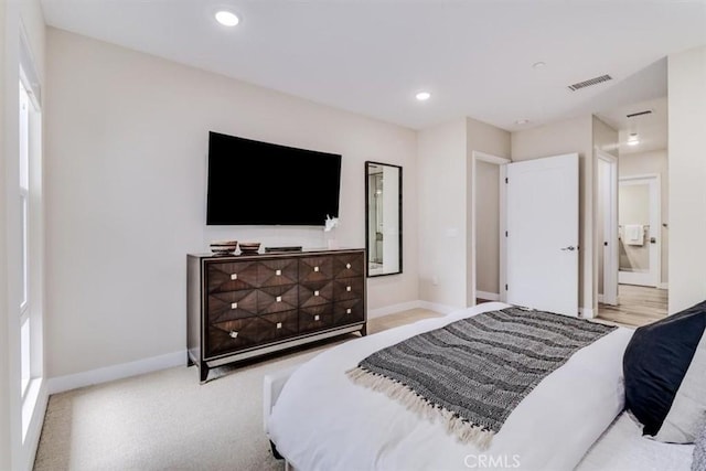 bedroom featuring connected bathroom and light colored carpet