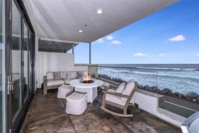 balcony featuring a view of the beach, a water view, and a fire pit