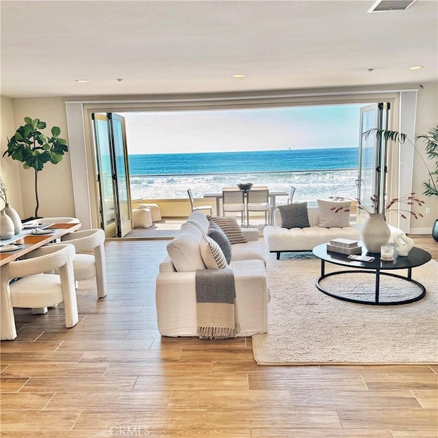 living room featuring a beach view, a water view, and a wealth of natural light