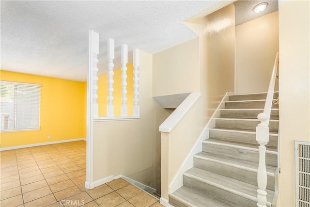 stairway with tile patterned floors and a textured ceiling