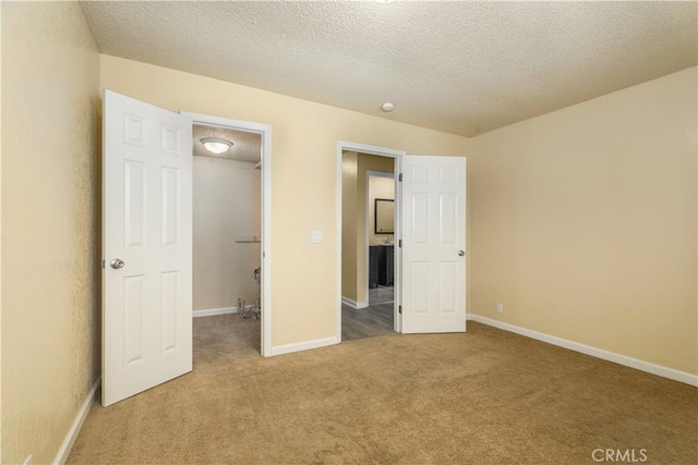 unfurnished bedroom with carpet flooring, a walk in closet, and a textured ceiling