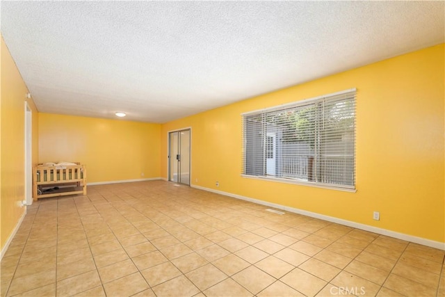 tiled empty room with a textured ceiling