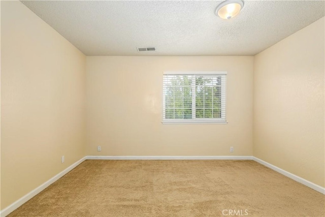 spare room featuring light carpet and a textured ceiling