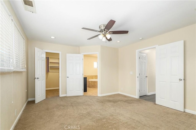 unfurnished bedroom featuring carpet, ceiling fan, a spacious closet, and connected bathroom