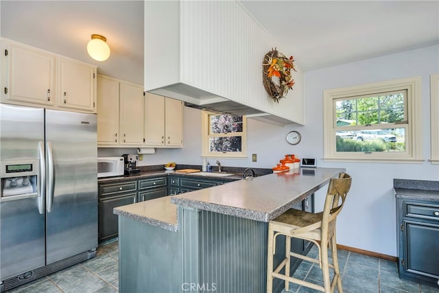 kitchen with sink, stainless steel fridge with ice dispenser, tile flooring, and kitchen peninsula