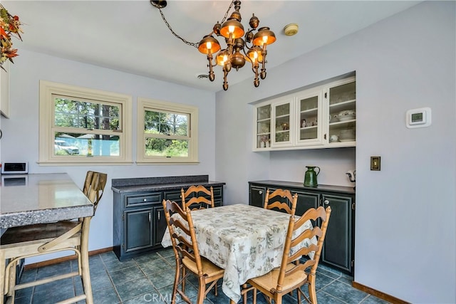 dining space featuring dark tile flooring and a chandelier