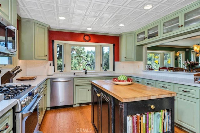 kitchen featuring tasteful backsplash, butcher block countertops, stainless steel appliances, light wood-type flooring, and sink