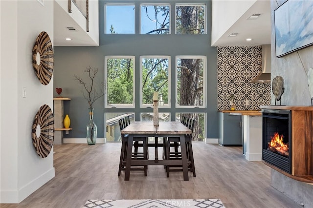 dining room featuring light wood-type flooring, a high ceiling, and wine cooler