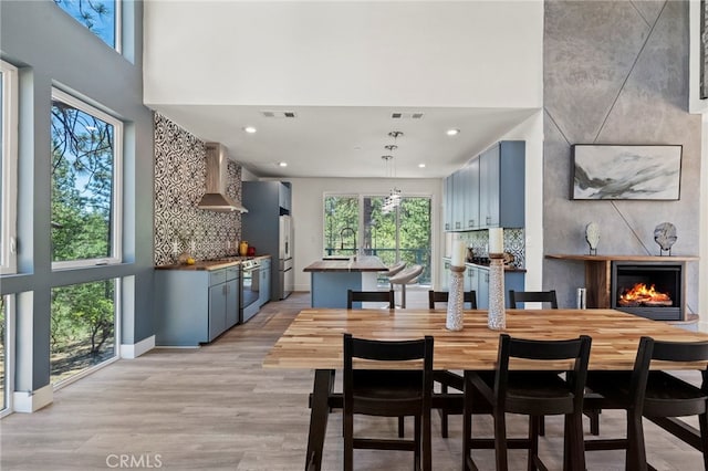 dining room with light wood-type flooring, sink, and a towering ceiling