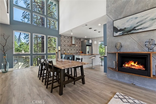 dining room with a towering ceiling and light wood-type flooring