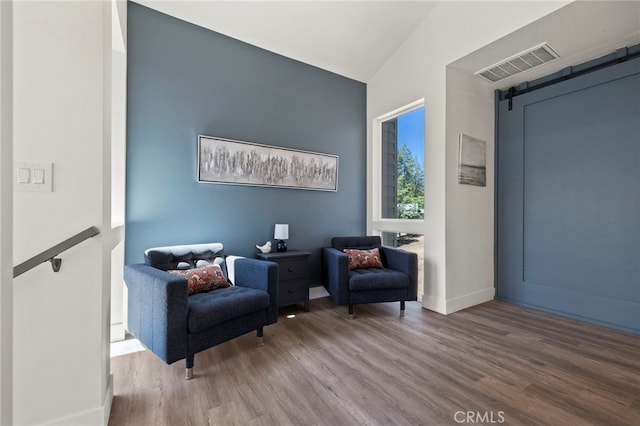 sitting room featuring hardwood / wood-style floors, a barn door, and lofted ceiling