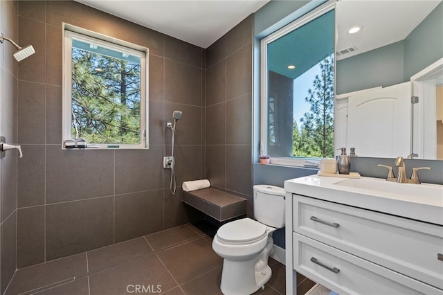 bathroom with tile patterned floors, vanity, toilet, and a tile shower