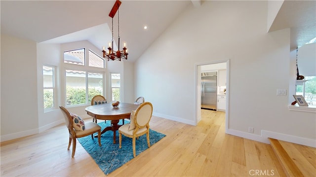 dining area with a notable chandelier, high vaulted ceiling, and light hardwood / wood-style floors