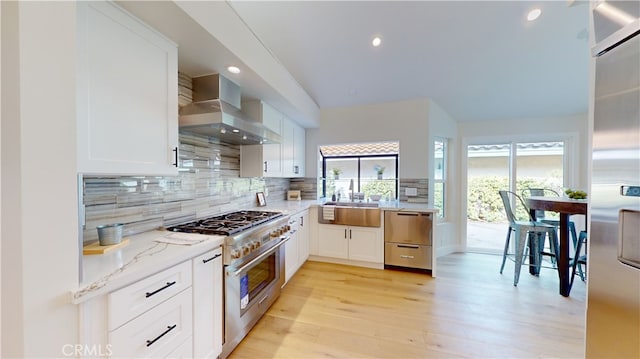 kitchen with white cabinetry, appliances with stainless steel finishes, and wall chimney range hood