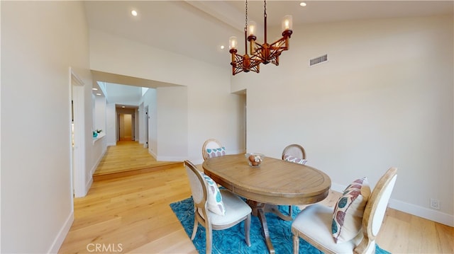 dining area featuring lofted ceiling, a chandelier, and light wood-type flooring