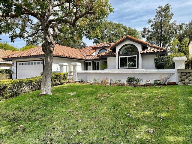 mediterranean / spanish-style house featuring a garage and a front lawn