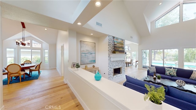 living room featuring high vaulted ceiling, light hardwood / wood-style floors, and a healthy amount of sunlight