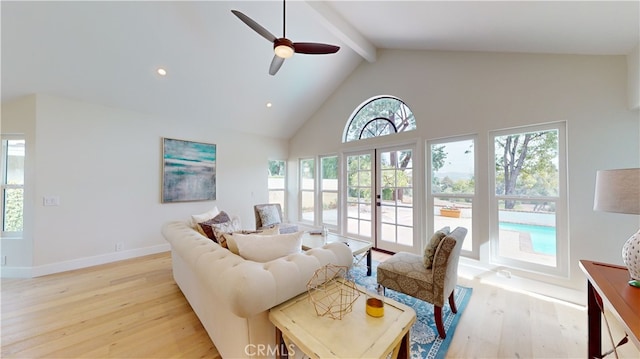 living room featuring beam ceiling, plenty of natural light, light hardwood / wood-style floors, and ceiling fan