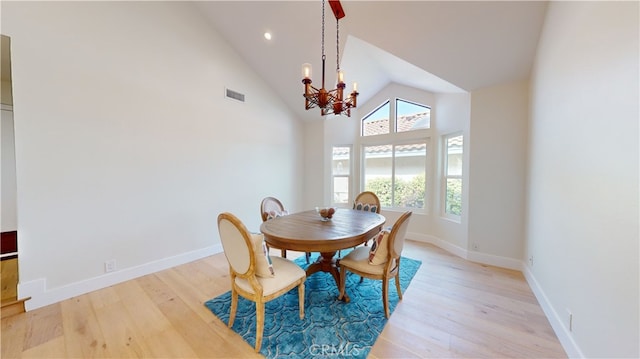 dining space featuring high vaulted ceiling, light hardwood / wood-style floors, and a notable chandelier