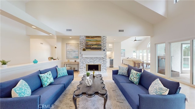 living room with a stone fireplace and high vaulted ceiling