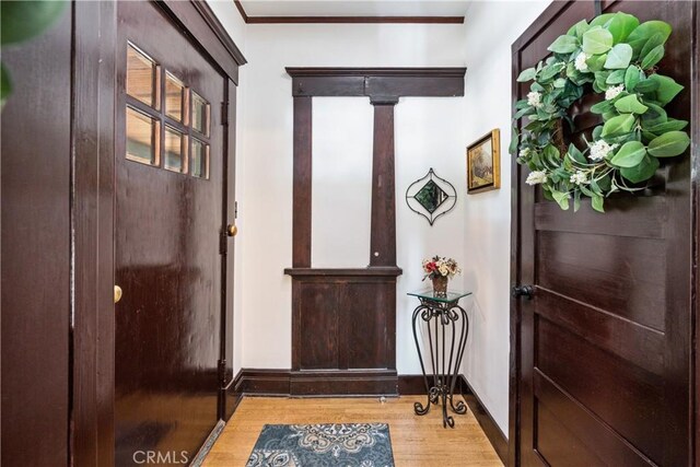 entryway with ornamental molding and light hardwood / wood-style flooring