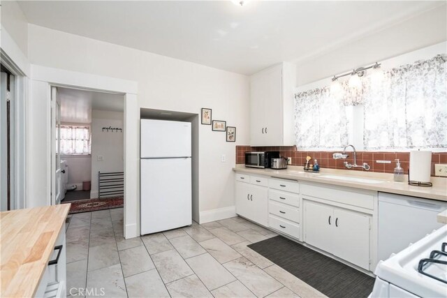 kitchen with white cabinetry, sink, tasteful backsplash, white refrigerator, and range