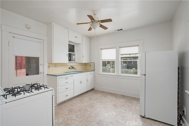 kitchen with backsplash, white appliances, ceiling fan, sink, and white cabinetry