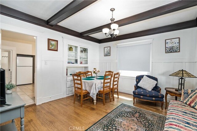 dining room featuring beamed ceiling, a notable chandelier, and light wood-type flooring