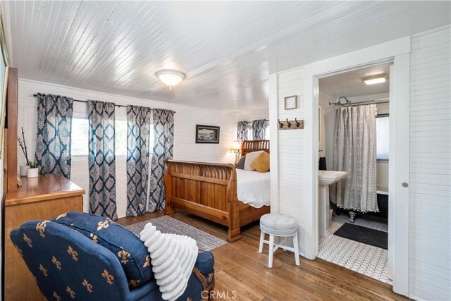 bedroom with connected bathroom and hardwood / wood-style flooring