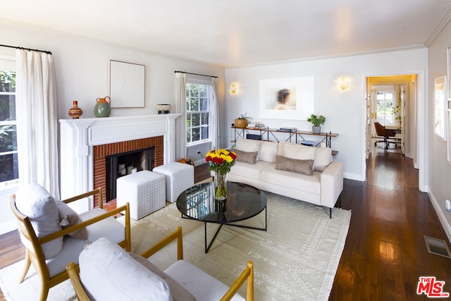 living room featuring dark hardwood / wood-style floors, plenty of natural light, ornamental molding, and a brick fireplace