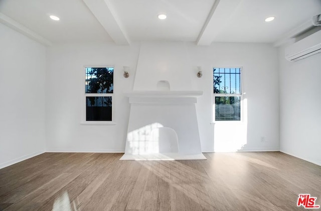 unfurnished living room with hardwood / wood-style floors, a wall unit AC, and beam ceiling