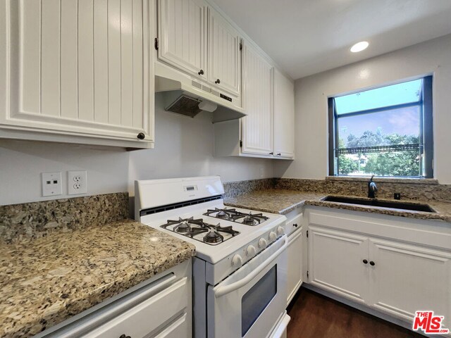 kitchen featuring white cabinets, sink, white gas range oven, light stone countertops, and dark hardwood / wood-style flooring