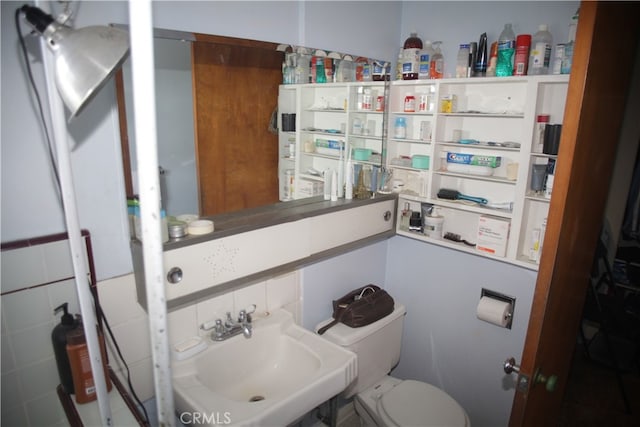 bathroom with tile walls, sink, and toilet