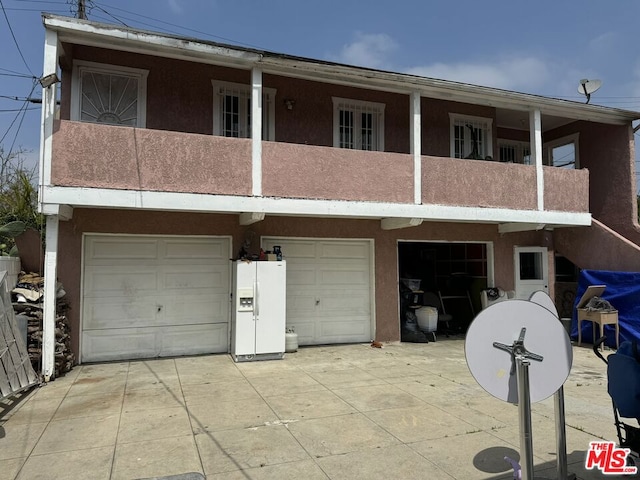 rear view of house featuring a balcony and a garage